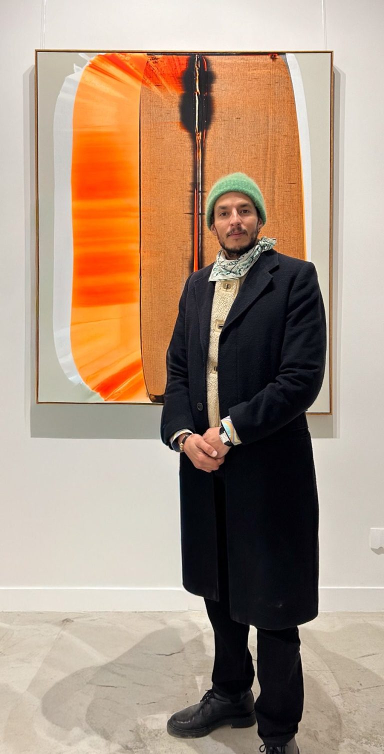 Hamza Djelassi chez H.D Galerie Fondateur de H.D Galerie, Hamza Djelassi posant devant une œuvre dans la galerie à Paris